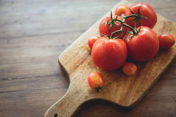 tomaten auf ein schneidebrett - cherry tomato image raw colors stock-fotos und bilder