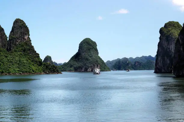 View of green islands in Halong Bay at day from a distance with white boats on the water, UNESCO World Heritage Site, Vietnam, Southeast Asia.