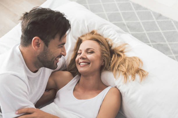 happy loving couple having fun on bedding - sensuality lifestyles cheerful comfortable imagens e fotografias de stock