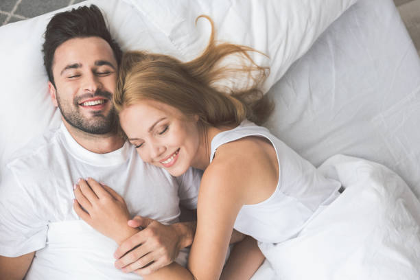 joyful loving couple luxuriating in bedroom together - sheet sleeping women bed imagens e fotografias de stock