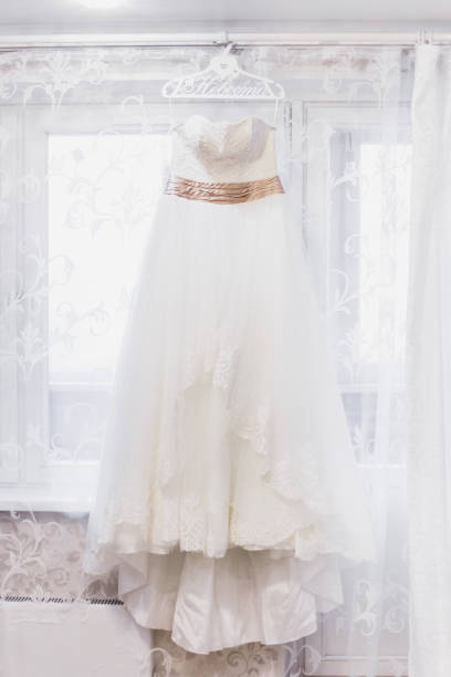 istock Beautiful white wedding dress hanging by window 860624902