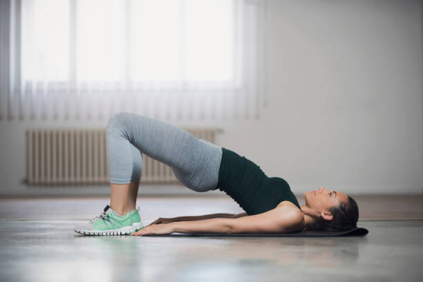 Tight Curves Workout Beautiful young woman doing hip lifts on the floor. buttock stock pictures, royalty-free photos & images