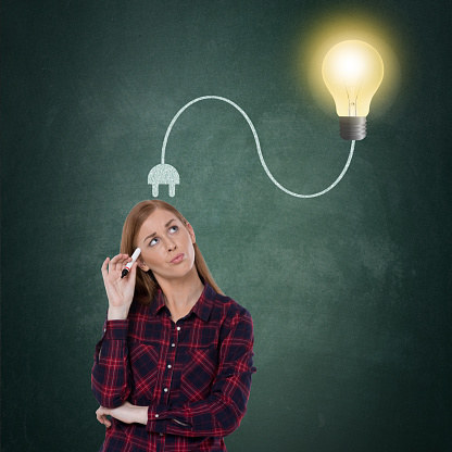 Thoughtful businesswoman with glowing light bulb plugged on her head