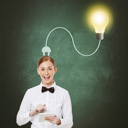 Portrait of businesswoman using digital tablet with light bulb plugged on her head