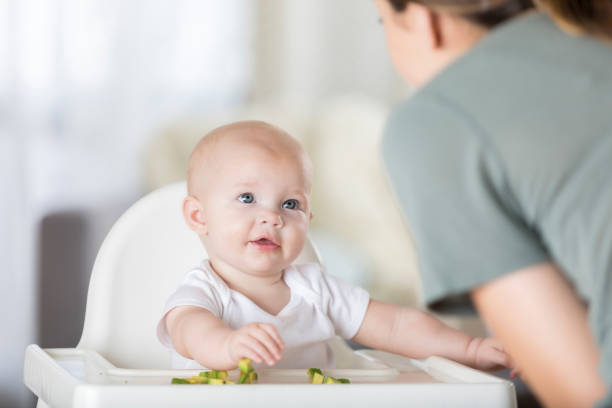 Shot of a young woman feeding her adorable baby girl at home
