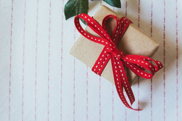istock Gift box, wrapped in recycled paper and red bow on on white tablecloth 860632266