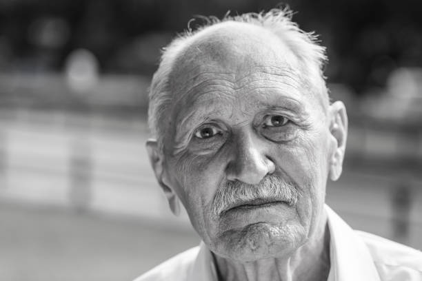 istock old man portrait, sitting on a bench in a park in summer 860632362