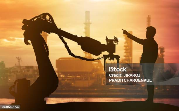 Industry 40 Technology Artificial Intelligence Trend Concept Silhouette Of Business Man Point Finger Forward To Heavy Automation Robot Arm Machine Vivid Sunset Sky And Smart Factory Background Stock Photo - Download Image Now