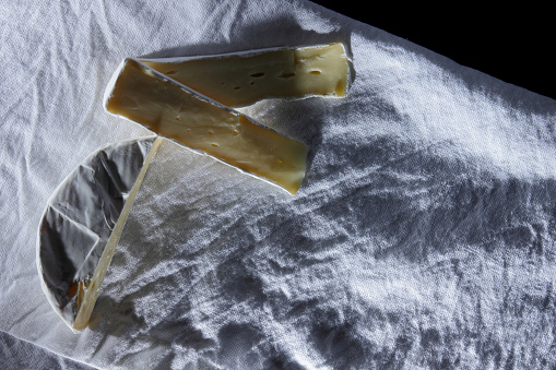 Camembert cheese cut on a white linen napkin in a retro style for the designer