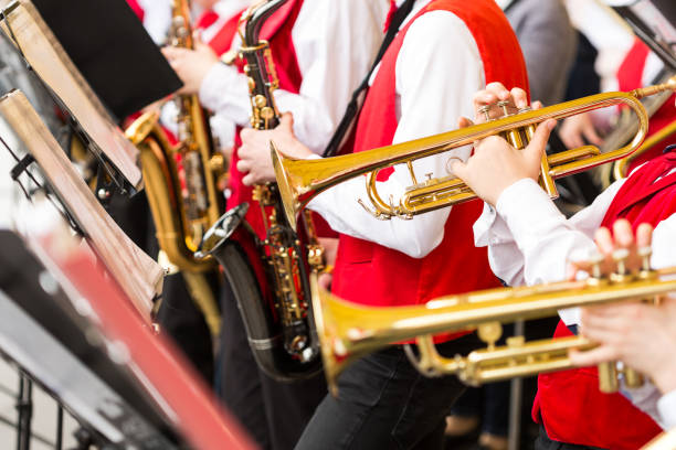 strumento musicale, banda di ottoni e concetto di orchestra - gruppo ravvicinato di musicisti che suonano su trombe e sassofoni in costumi da concerto rossi, mani maschili con attrezzature lucide, messa a fuoco selettiva - jazz ballet foto e immagini stock