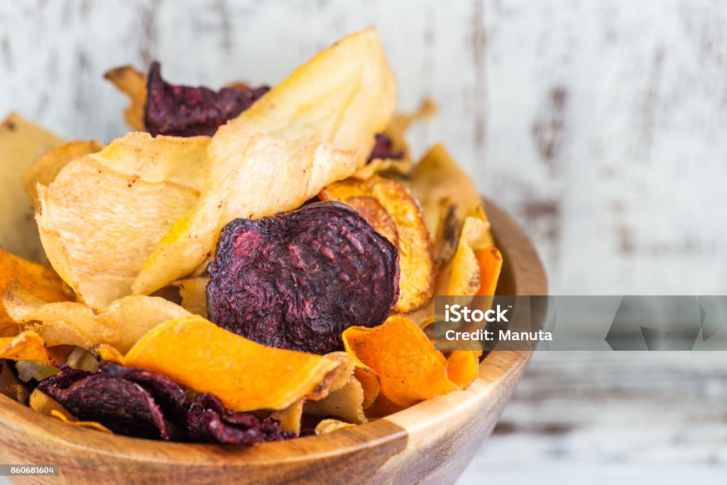 Bowl of Healthy Snack from Vegetable Chips, Crisps Bowl of Healthy Snack from Vegetable Chips, such as Sweet Potato, Beetroot, Carrot, Parsnip on Light Wooden Background Potato Chip Stock Photo
