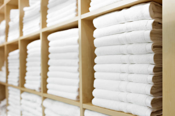 blanco hotel toallas dobladas y apiladas en un estante - toalla fotografías e imágenes de stock