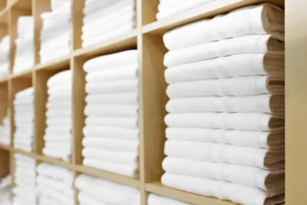 Photo of Fresh White Hotel Towels Folded and Stacked on a Shelf