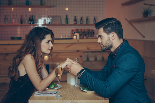 side view of young couple in love having romantic dinner together in restaurant