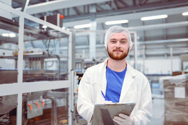 istock Young Handsome Smiling Scientist With Clipboard Posing in Factory 860700650