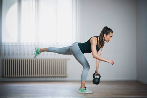 Body Toning Young woman doing single-leg kettlebell deadlift. kettlebell stock pictures, royalty-free photos & images