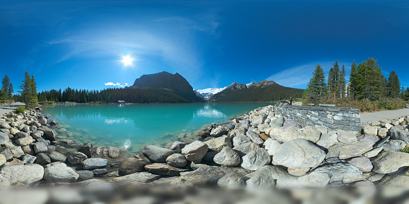 equirectangular panorama of Lake Louise on a bright sunlit summer day with turquoise green water, seen from the lake shore