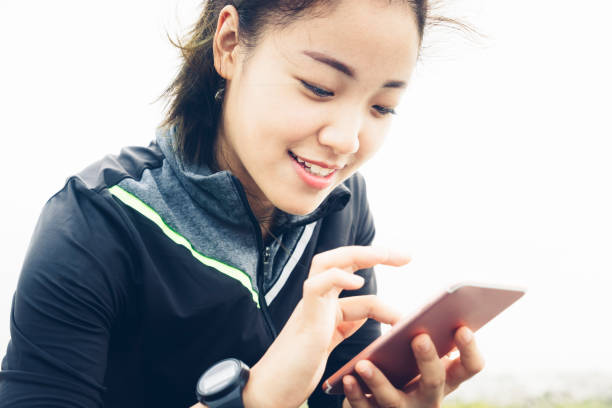 istock cheeerful woman sitting at roadside playing smartphone 860711084