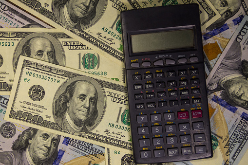Black calculator on the American one hundred dollar bills background
