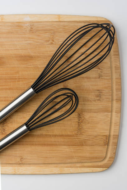 istock Two Whisks Angled on a Wooden Cutting Board 860715104