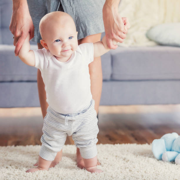 istock Baby concentrates while learning to walk with mom 860715336