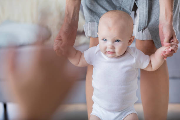 istock Adorable baby walks with assistance toward Dad 860715338
