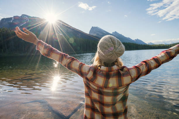 istock Young woman arms outstretched by mountain lake 860736044