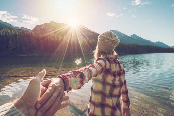 日の出山の湖に男をリードする若い女性私に従う - dawn mountain range mountain canadian rockies ストックフォトと画像