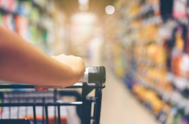 Asian woman's hand with supermarket, trolley and many objects that are blurred background. stock photo