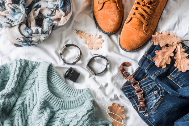 istock Flat lay women's clothing for autumn walks, top view. Brown suede boots, jeans, a blue pullover, scarf, bracelets, watches, headphones, perfume on a light background. Fashion concept 860753038