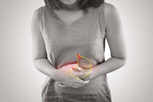 woman suffering from gastroesophageal reflux disease or acid reflux standing against gray background, female anatomy concept - cancro gástrico imagens e fotografias de stock