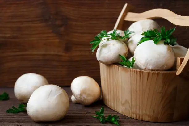 Fresh mushrooms in a wooden basket on a wooden background