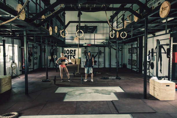 Young couple is satisfied after lifting weights in gym.