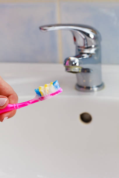 istock Hand holding toothbrush in bathroom 860771842