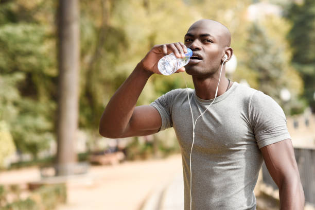istock Young black man drinking water before running in urban background 860771864