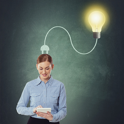 Portrait of businesswoman using digital tablet with light bulb plugged on her head