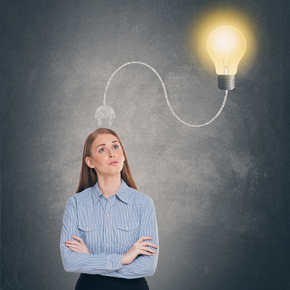 Thoughtful young woman with glowing light bulb plugged on her head