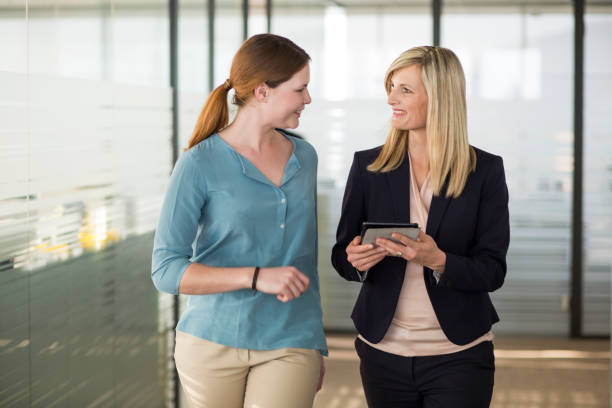 istock Two female colleagues talking while walking in the office corridor 860794420