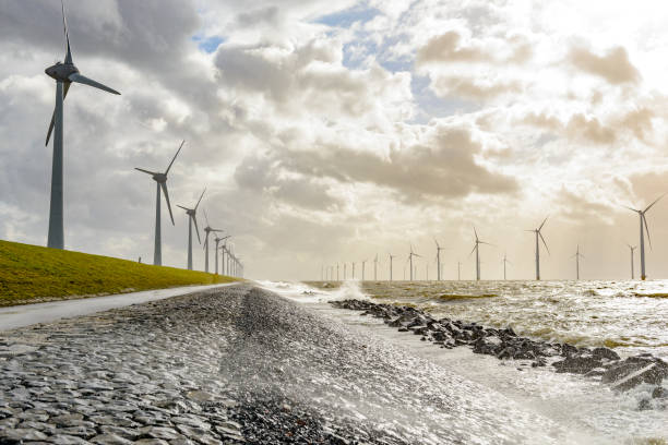 Wind turbines on land and offshore in a storm Wind farm with rows of wind turbines both on land and offshore during a winter storm at the shore of the IJsselmeer in the Noordoostpolder, Flevoland, The Netherlands. flevoland photos stock pictures, royalty-free photos & images