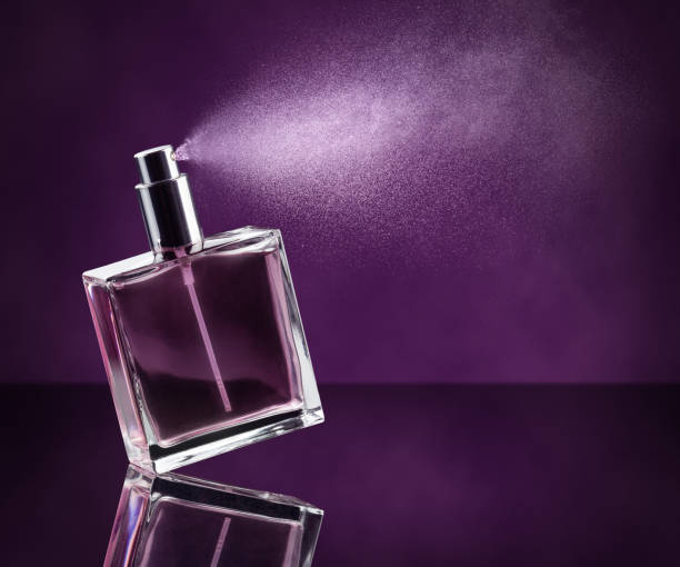 parfüm aufsprühen auf lila hintergrund - parfüm fotos stock-fotos und bilder