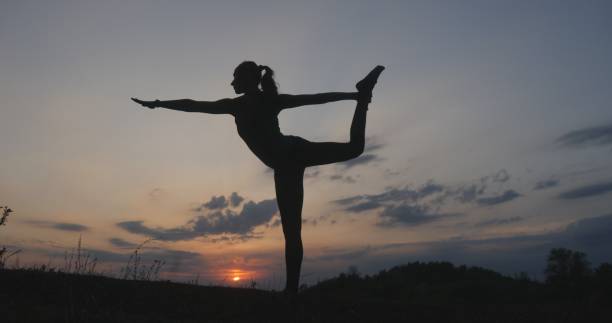 istock Silhouette young woman practicing yoga at sunset 860808646