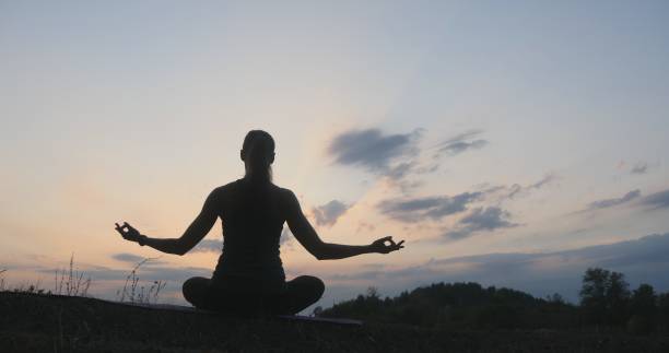 istock Silhouette young woman practicing yoga at sunset 860808890