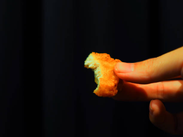 istock Bitten nugget held by right hand, black curtain background 860812650
