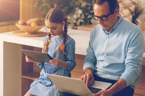 istock Serious little girl and her dad working with digital devices 860812886