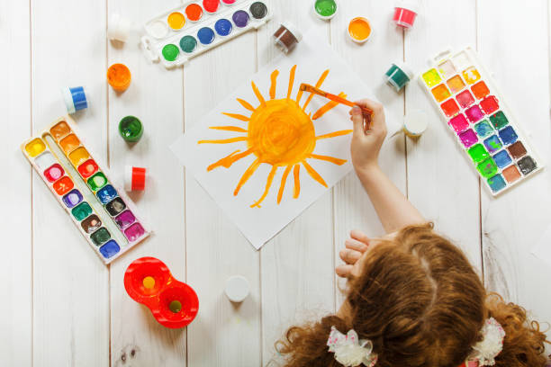istock Child hand with brushes drawing yellow sun. 860816892
