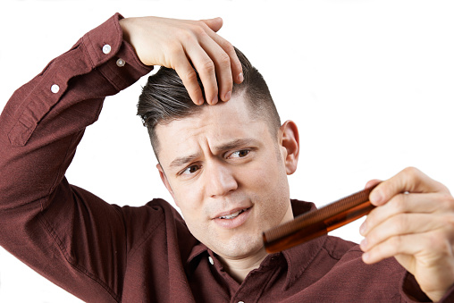 Hombre con peine preocupado por caída del cabello photo