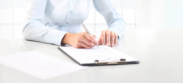 istock Woman's hands writing on sheet  in a clipboard with a pen, isolated on desk 860825278