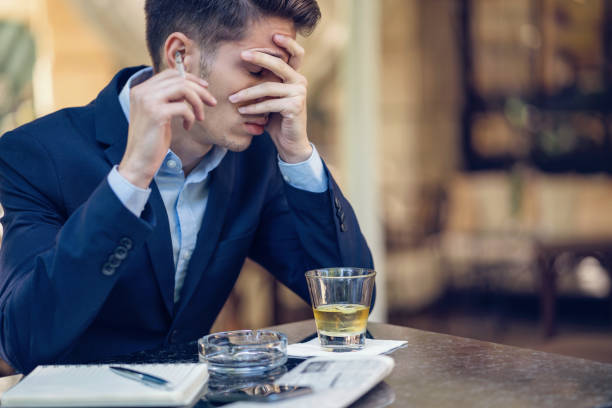 istock Young upset businessman smoking cigarette and drinking alcohol 860830236