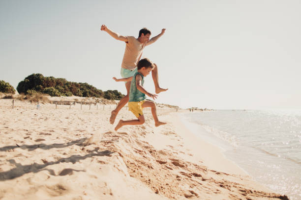 Summer day on the beach Photo is showing young father with his son, enjoying their fulfilled summer vacation by the ocean children at the beach stock pictures, royalty-free photos & images