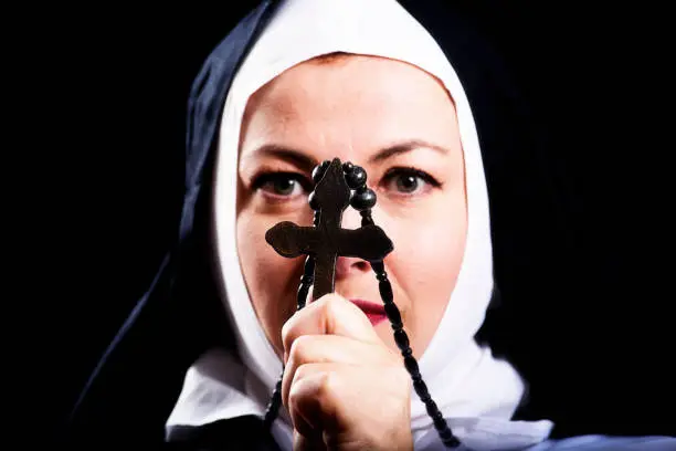 Photo of Nun holds a crucifix infront of her face